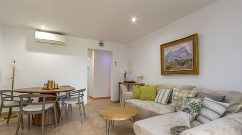 Spacious living-dining room with neutral-toned sofa, wooden round table and modern décor.