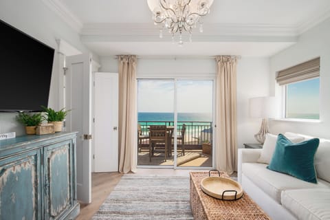 The living room features a comfortable sofa, TV, and stunning Gulf views.