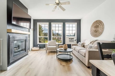 Living room with a stunning fireplace feature, Smart TV, window A/C unit and cozy seating with a queen-sized pull-out sofa bed.