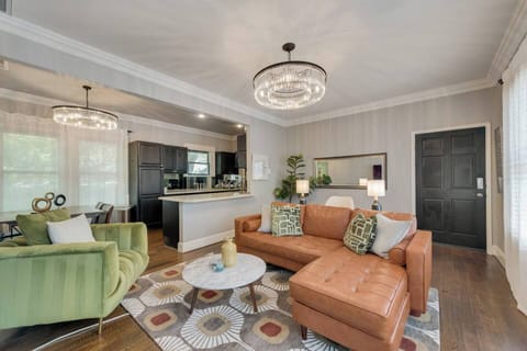 Bright open living room featuring a leather chaise sofa and a stylish green velvet chair, blending comfort and elegance.