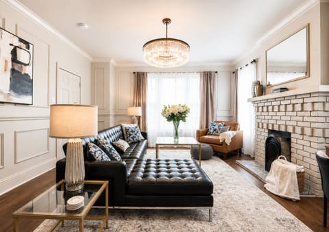 Relax in style in our living room, complete with a luxurious leather sectional, a charming brick fireplace, and bright, modern decor throughout, creating a sophisticated and inviting atmosphere.