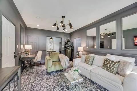 Open Living Room . In the corner, you'll find a dedicated office workspace, perfect for getting some work done. Mirrors on the walls enhance the natural light, while a beautiful chandelier adds a touch of elegance and warmth to the room.