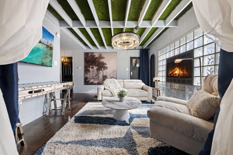 Sophisticated Living Area – Designer furnishings, statement chandelier, and 65″ smart TV create a space of comfort and style.