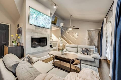 The living area boasts beautiful seating, a large TV, and chic, stylish decor throughout, all centered around a cozy fireplace, creating the perfect spot to relax and unwind.