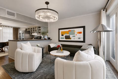 Sun-filled living room with crystal chandelier and art as you enter the space. 