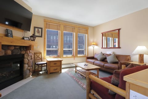 Cozy up by your stone fireplace in this warm living space with leather seating and mountain village views.