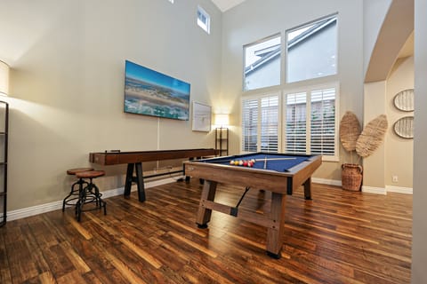 Game room features high ceilings, a pool table, shuffleboard, and giant Smart TV.