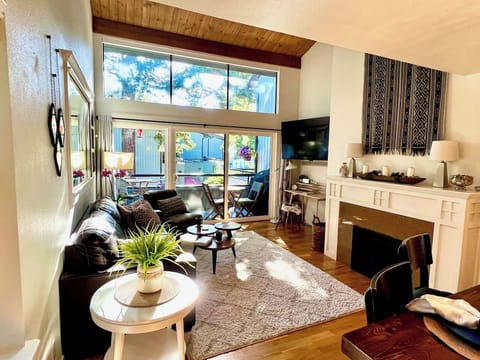 Living room with full wall of windows so you can enjoy the greenery on a sunny day or sit by a cozy fire on quiet fall and winter days