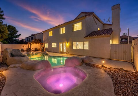 Resort-style yard with lit spa, pool, and pergola lounge.