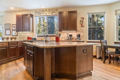 The fully equipped kitchen is a beautiful space with granite countertops, stainless steel appliances, and an over-the-sink window with tree views.