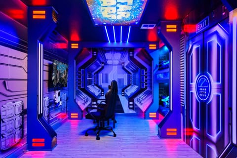 Immersive space-themed gamer’s paradise with bunks, LED lights, and consoles.

