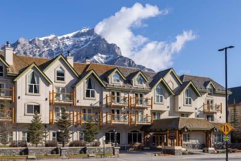 Three-story building on Banff Avenue with timber balconies and Cascade Mountain rising behind