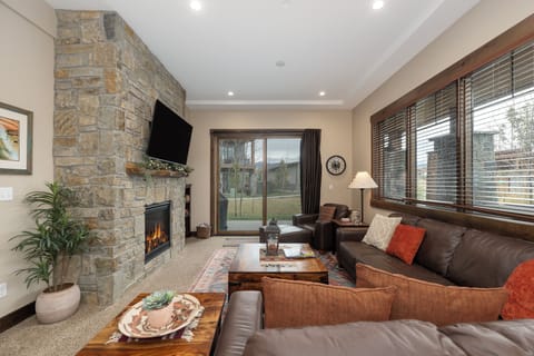 Unwind in your cozy living room featuring a stunning stone fireplace, plush sectional seating, and warm ambiance perfect for relaxing evenings.