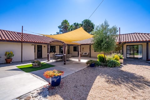 Outdoor patio with seating, shade sails, and desert landscaping.