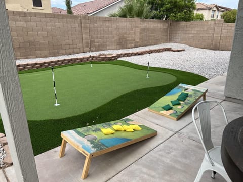 Putting green and corn hole beside outdoor seating and grill