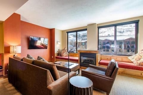 Spacious living room with cozy seating, a fireplace, and large windows with beautiful mountain and resort views.