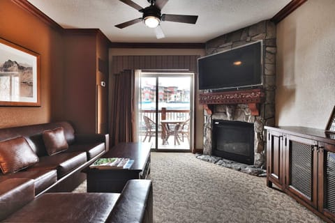 - Living room with fireplace and flat screen TV  
- Sliding doors open to private balcony seating  
- A cozy retreat with mountain resort views