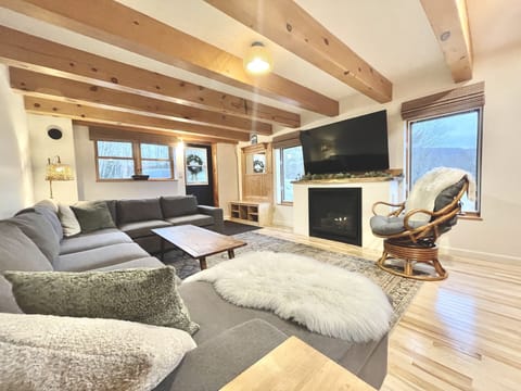Living room with sectional couch, gas fireplace and 60” Roku TV.