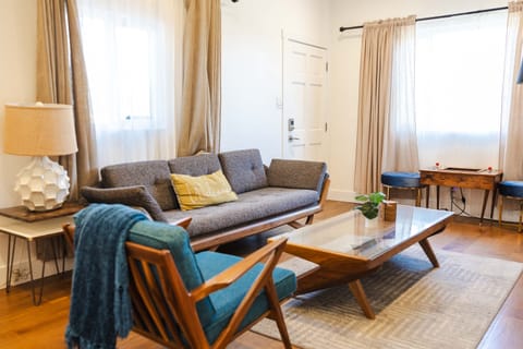 Living room with couch, chair, side table, coffee table, arcade game for 2 and television connected to the internet.