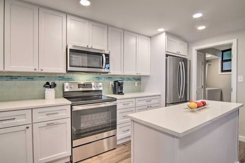 White cabinets with white quartz countertops and new stainless appliances in the kitchen.