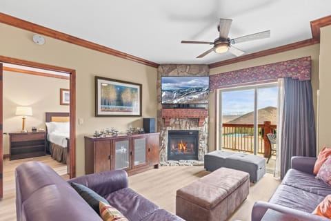 Cozy living room with stone fireplace, comfortable seating, and mountain views from your private balcony.