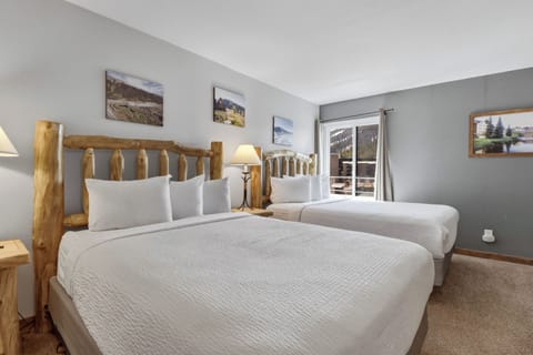 Unwind in your comfortable twin bedroom with rustic log beds, crisp linens, and mountain artwork creating a cozy alpine retreat.