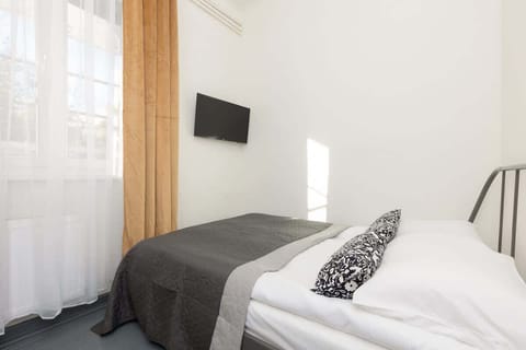 A cozy bedroom with a black metal bed frame, gray bedding, and a wall-mounted TV.

