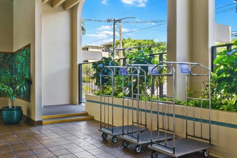 The property's welcoming entrance features lush tropical greenery and convenient luggage cart access for a smooth arrival experience.