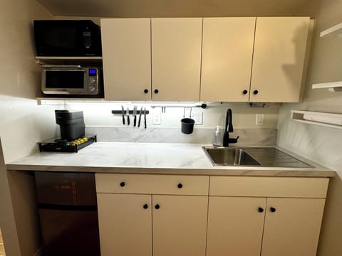 Fridge, cooktop, microwave, toaster, Nespresso, blender, utensils, dining area.