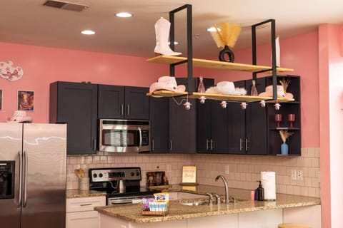 Sassy meets stylish in this fully equipped kitchen with darkk cabinetry, granite counters, and whimsical pink-and-white cowgirl hat accents. Whether you’re cooking or just pouring champagne, it’s all part of the fun.
