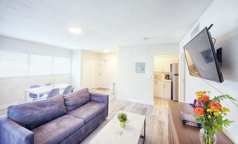 Featuring living room with 40" smart TV, and sofa queen bed. Apartment entry and kitchen entry in view.