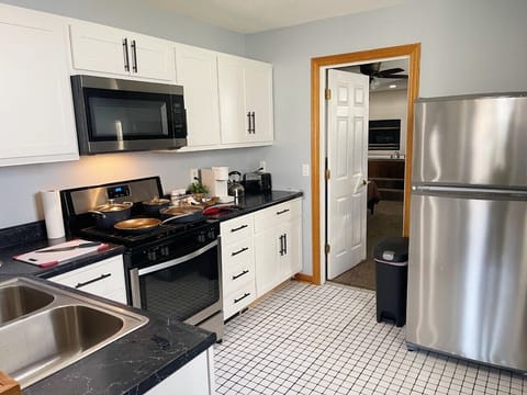 Kitchen stocked with cookware, dinnerware, silverware & stainless appliances.