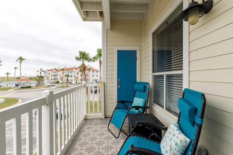 Unwind on your private balcony with comfortable lounge chairs overlooking tropical palms and coastal architecture.