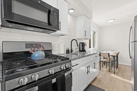 This bright and contemporary galley kitchen features granite countertops, stainless steel appliances, and a cozy dining nook bathed in natural light — perfect for enjoying meals at home.