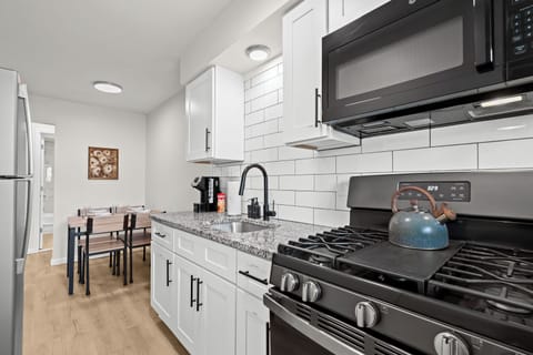 Fully equipped kitchen with granite countertops, stainless steel appliances, and a cozy dining area for four.