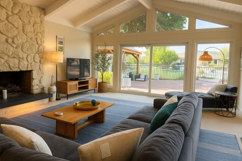 Sunlit living room framed by soaring ceilings & garden views