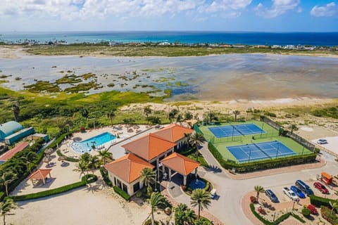 Aerial view of the Gold Coast clubhouse with amenities including swimming pool, gym and tennis courts, all set against Aruba’s beautiful coastline and open island scenery with fantastic views and a great place to relax