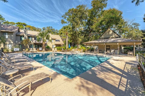 The community pool is tucked into a serene, wooded setting, offering a peaceful place to unwind beneath mature oaks and palms.