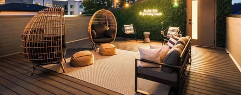 Rooftop at dusk with neon sign glow, egg chair, and city view, come back here after catching a show or grabbing pancakes nearby. Reserve with Misfit Homes