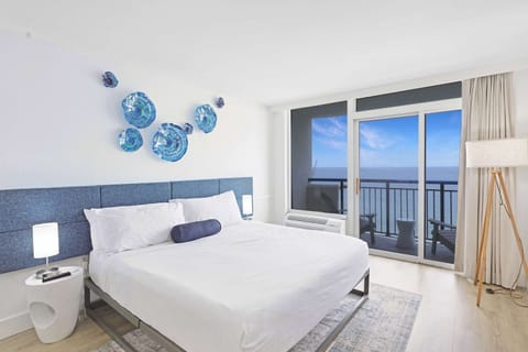 Inviting bedroom with a cozy King bed, vibrant seaside décor, and private balcony access.