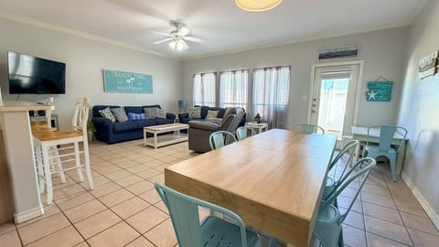 Relax in your spacious open-plan living area with comfortable seating, dining for eight, and coastal decor creating the perfect beach house atmosphere.