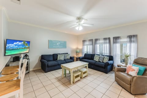 Relax in your spacious living room with comfy seating, beach-themed decor, and entertainment center for cozy evenings after exploring.