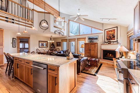 Bright and airy open-concept kitchen and living space with vaulted ceilings, rustic wood finishes, and a cozy fireplace for mountain lodge vibes.