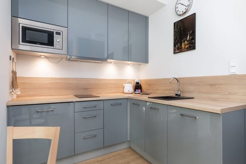 A modern kitchen with gray cabinetry, wood countertops, and built-in appliances, designed for efficiency and style.