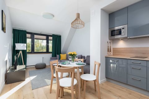 A cozy dining space with a round table set for four, adorned with vibrant green accents and natural light.