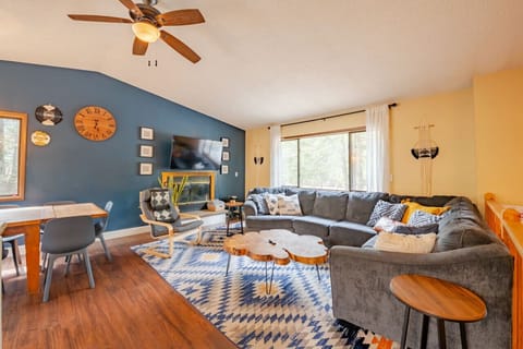 Gray sectional sofa, wood slice table, blue accent wall, and cozy dining area.