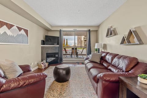 Living room with an electric fireplace, Smart TV, cozy seating and walkout access to the ground-floor patio.