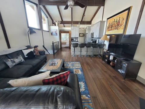 Living room with 65" smart TV looking into Kitchen and upstairs Queen bedroom