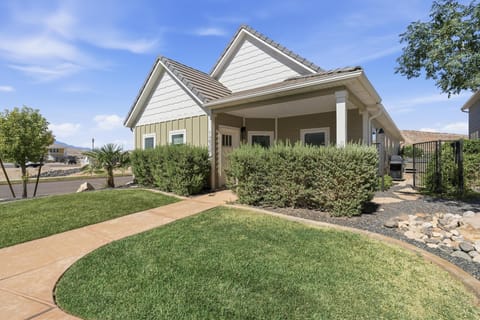 Single-level house exterior with beige siding, white trim, covered porch, and landscaped front yard.