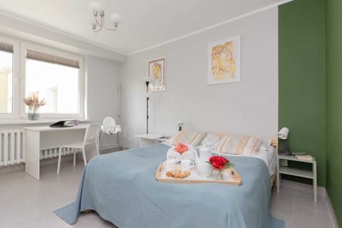 A bright and inviting bedroom featuring a comfortable double bed with soft linens, a nightstand, and a large window.

